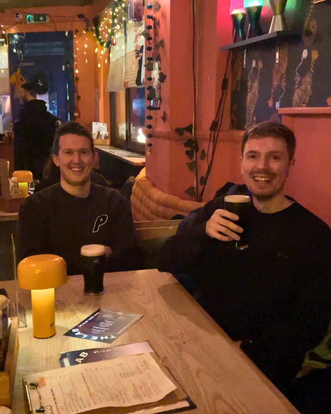 Dean and Liam sitting at a pub table on the first night of Empty Chairs